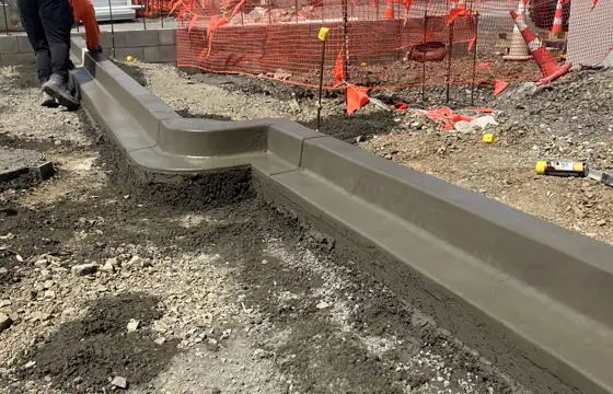Slip-form machine extruding kerb on site